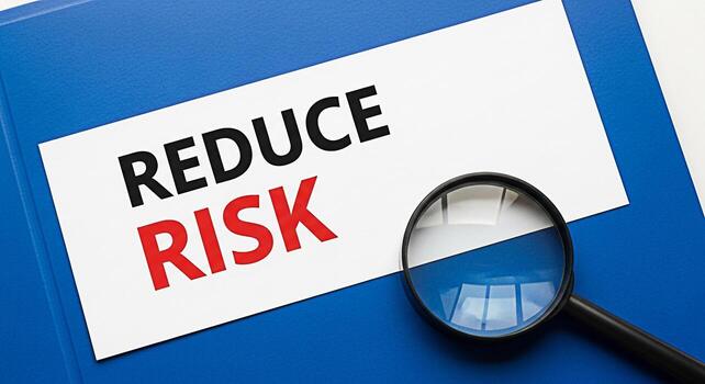 Magnifying glass examining a document on a blue folder focusing on the phrase Reduce Risk symbolizing careful analysis and mitigation strategies in a business or financial context conveying a sense of photo
