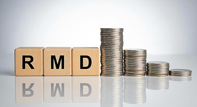 Wooden blocks spelling RMD next to stacks of coins on a reflective surface representing Required Minimum Distribution in a financial planning context conveying a sense of financial awareness and retir photo