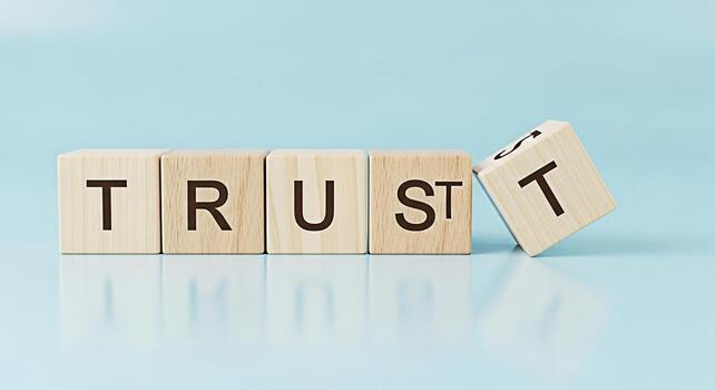 de madera bloques ortografía el palabra confiar en un ligero azul superficie con uno bloquear ligeramente inclinado transporte un sentido de vulnerabilidad fragilidad y el importancia de mantener confianza y fiabilidad yo foto