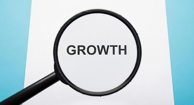 A magnifying glass focuses on the word GROWTH on a white sheet of paper symbolizing business development and personal progress in a bright optimistic environment suggesting potential and opportunity photo