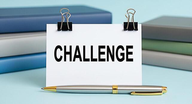 Challenge concept A motivational message displayed on a white card with binder clips resting on a light blue surface with a pen symbolizing overcoming obstacles and achieving goals in a business setti photo