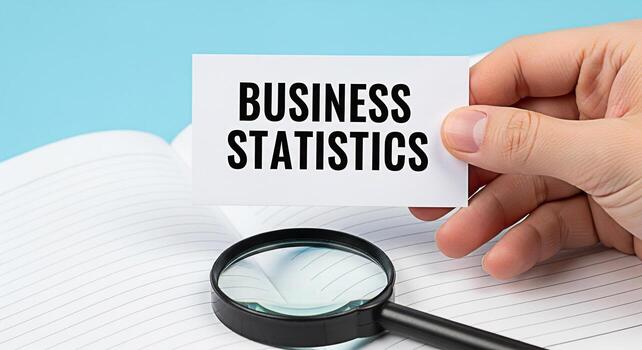 Closeup of a hand holding a business statistics card over an open notebook with a magnifying glass on a light blue background representing analysis research and the importance of datadriven decisionma photo