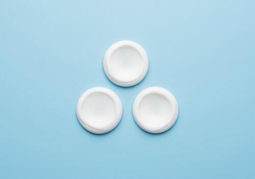 Three white cosmetic cream dollops arranged in a triangle shape on a light blue background. photo