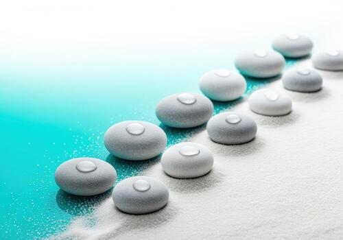 Row of smooth spa stones with clear water droplets transitioning from turquoise water to sand photo