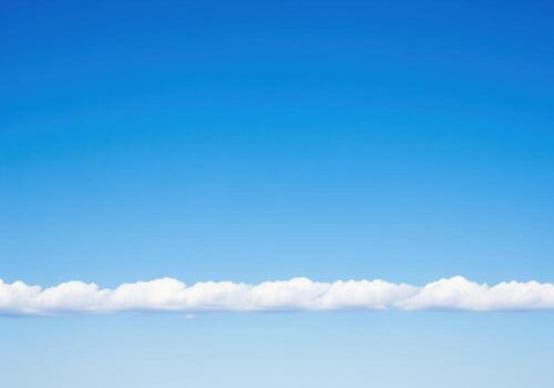 Expansive azure sky background with a perfectly aligned band of fluffy white cumulus clouds photo