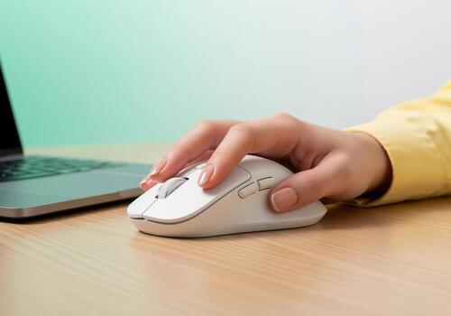 Woman hand using white wireless computer mouse for browsing and working on a laptop photo