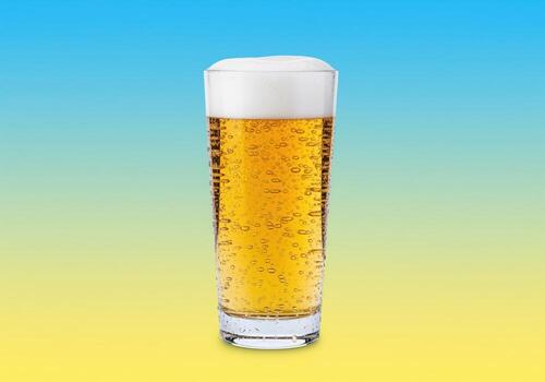 Refreshing glass of cold lager beer with condensation and foam head on a bright summer background. photo