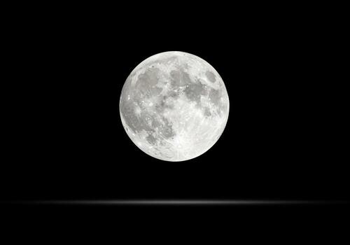 Pristine full moon glowing brightly in the deep dark night sky and outer space photo