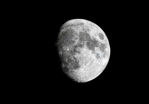 Detailed view of the gibbous moon surface showing craters and texture in a black sky photo