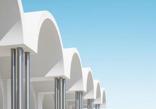 Repeating white arches and sleek metallic columns of a modern minimalist facade. photo