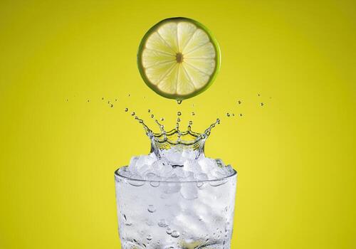 Refreshing lime slice dropping into a glass of crushed ice creating a dynamic splash photo
