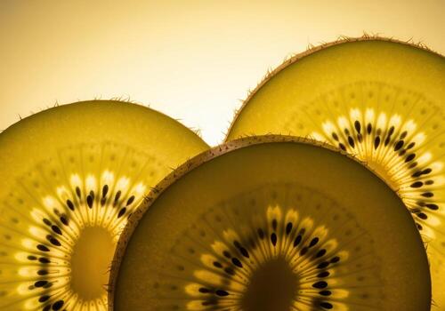 Translucent golden kiwi slices overlapping in a bright, warm macro close up. photo