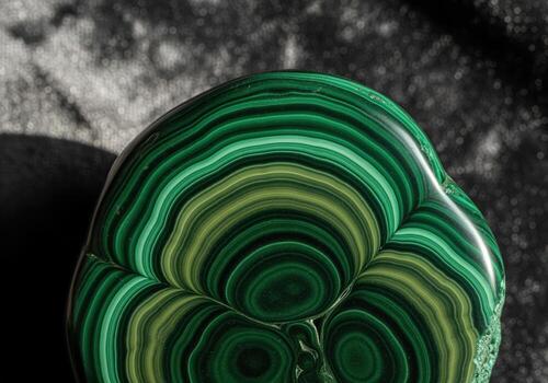 Polished malachite mineral stone with intense green concentric circular patterns photo