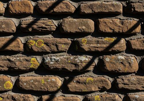 muy texturizado rústico marrón Roca pared superficie con gris mortero y amarillo liquen. foto