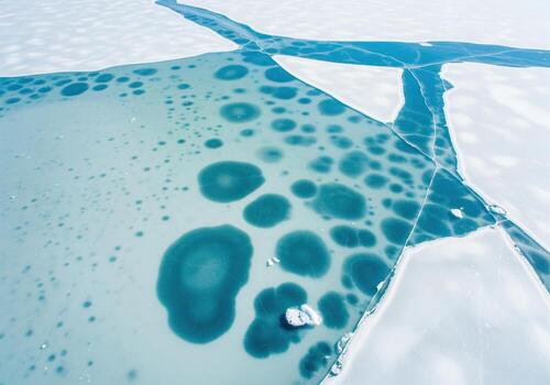 Aerial view of frozen lake ice with turquoise methane bubble patterns and cracks photo