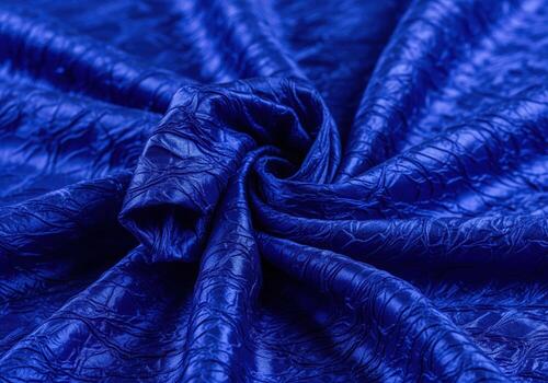 Vibrant deep sapphire blue crushed silk fabric texture background with dramatic folds and swirl pattern photo