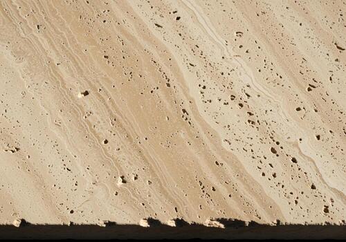 Natural beige travertine stone texture background with porous surface and diagonal veins. photo