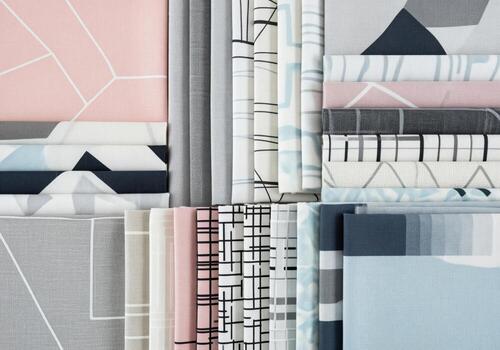 Stacked modern fabric swatches displaying geometric patterns and a pastel color palette. photo