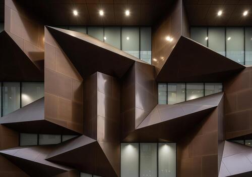 Modern architectural facade detail with sharp angular geometric bronze panels photo