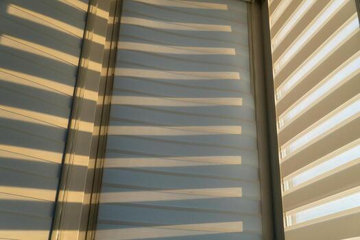 A window with blinds and sunlight shining through photo