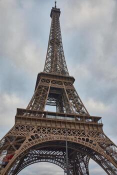 View of the Eiffel Tower in Paris, built for the 1889 World's Fair, with a cloudy sky and a metal structure photo