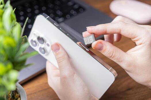 Human hand carefully installing a new nano SIM card into a sleek white smartphone, symbolizing essential mobile communication setup, activation, and network service photo