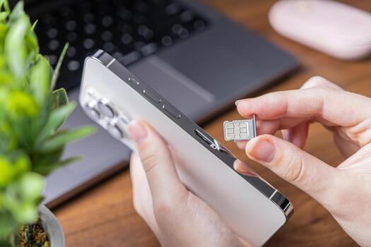Person's hand holds a sleek smartphone, preparing to insert a nano SIM card, representing essential mobile network setup and modern telecommunications technology photo