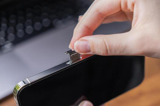 Person's hand inserts a tiny SIM card into a modern smartphone, signifying essential mobile network connectivity, telecommunication setup, and global digital communication services photo