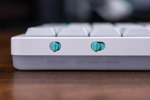 Stylish mechanical keyboard side with vibrant teal toggle switches managing WIN MAC operating system and WIRED WIRELESS connectivity for ultimate computer versatility photo