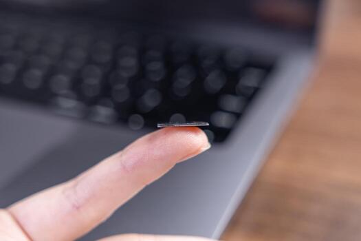 A human finger balancing a thin microchip, representing advanced data storage, miniaturization, and powerful modern electronic computing technology photo