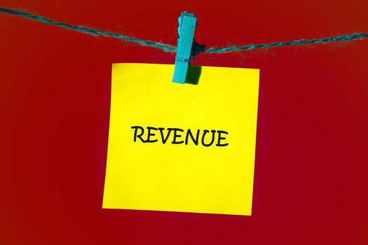 un amarillo cuadrado Nota con el palabra ingresos escrito en eso es cortado a un cadena. el antecedentes es sólido rojo, ofrecimiento un sencillo y enfocado presentación foto