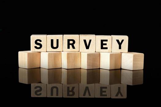 Wood blocks spell out the word SURVEY against a black background. The blocks reflect on the surface below, highlighting the importance of data collection and analysis photo