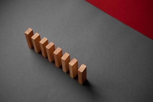 Domino has Fallen in a Row. Domino theory. Effect. Hand with Finger is Pointing and Pushing the Falling Wood Blocks. Risk , Revolution Concept. Affect Business. Closeup. Manifestation. Red photo