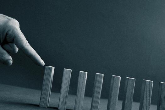 Domino has Fallen in a Row. Domino theory. Effect. Hand with Finger Pointing Pushing the Falling Wood Blocks. Risk Management, Revolution Concept. Affect Business. Closeup. Manifestation. Red photo