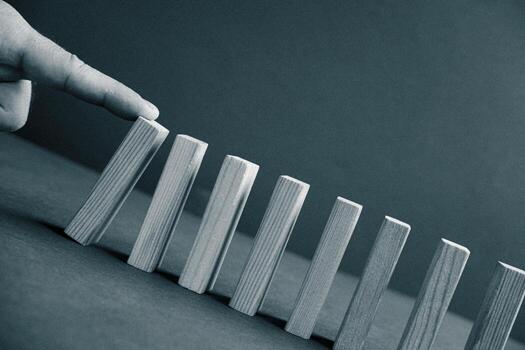 Domino has Fallen in Row. Domino theory. Effect. Hand with Finger is Pointing and Pushing the Falling Wood Blocks. Risk Management, Revolution Concept. Affect Business. Closeup. Manifestation. Red photo