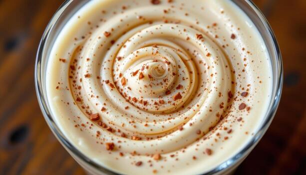 A mousse in a clear glass cup reveals subtle layering, with creamy tones blending softly in a visually harmonious composition. photo