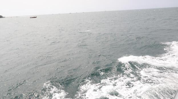 Boat sails on the open ocean during a cloudy day, leaving a trail of white foam and waves, creating a sense of freedom and adventure. photo