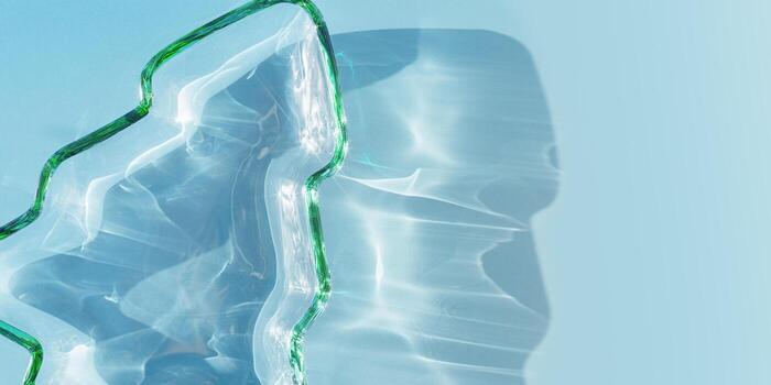 Color glass plate form as New Year tree, Christmas tree from transparent green glowing glass at sunbeams, caustics effect, star filter, gradient color banner. Sunlight and shadow, sparkling texture photo