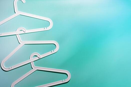 White Clothes hangers as creative minimal composition gradient background of teal tint, Plastic racks creating modern and geometric aesthetic, top view photo vivid color, creative fashion pattern