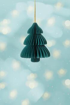 Minimal Christmas fir tree ornament of eco-friendly green paper hanging on golden string, on green background with golden bokeh. Festive Winter holidays xmas decor, side view, minimal style design. photo