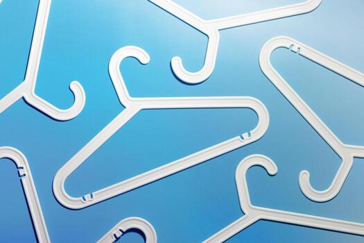 White Clothes hangers as creative minimal composition on soft blue gradient background, Plastic racks creating modern and geometric aesthetic, top view, flat lay creative photo, smooth lines pattern photo