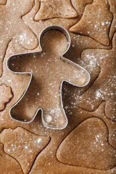 Cooking ginger cookies, Christmas and New Year traditional cookies in shape of gingerbread man, rolled out dough with cut out dough figures, closeup texture, top view, pattern on dough photo