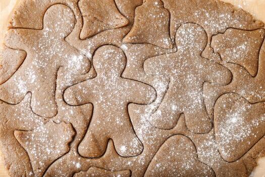 Cooking ginger cookies, Christmas and New Year traditional cookies in shape of gingerbread man, raw rolled out dough with cut out dough figures, closeup texture, top view, pattern on dough photo