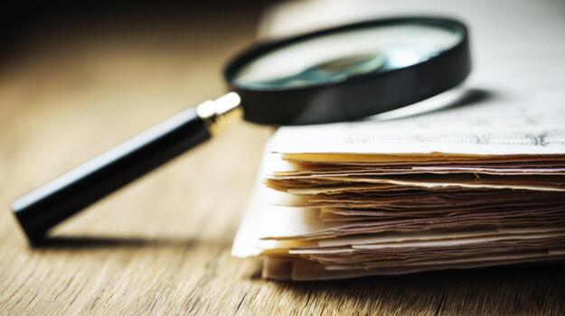 Magnifying glass examines documents on a wooden table photo