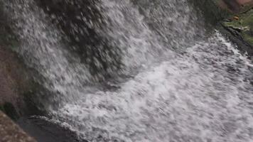 Close-up view of a cascading waterfall, creating a powerful and dynamic flow of white water against a textured rock edge video