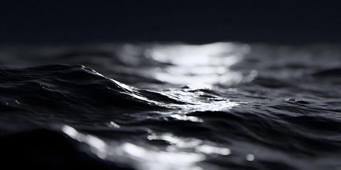 Dark water ripples gently under a soft light creating an abstract texture of waves and reflections photo