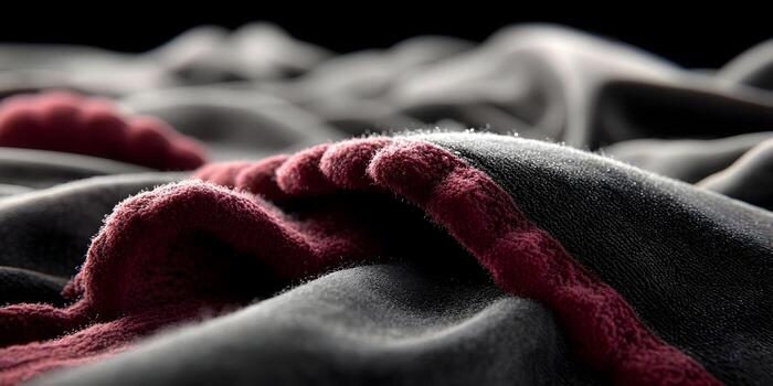 Deep red textured structures lie on a dark grey fuzzy material in this macro view photo