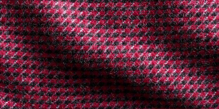 A close up view of a fuzzy red and black houndstooth pattern fabric texture photo