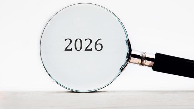 A magnifying glass is held over the number 2026, emphasizing the year and suggesting a closer look at what the future holds or the details within that specific time frame photo