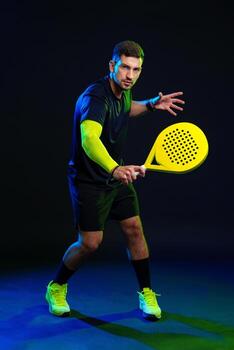 Practicing padel with a bright racket in a dramatic lighting setting photo